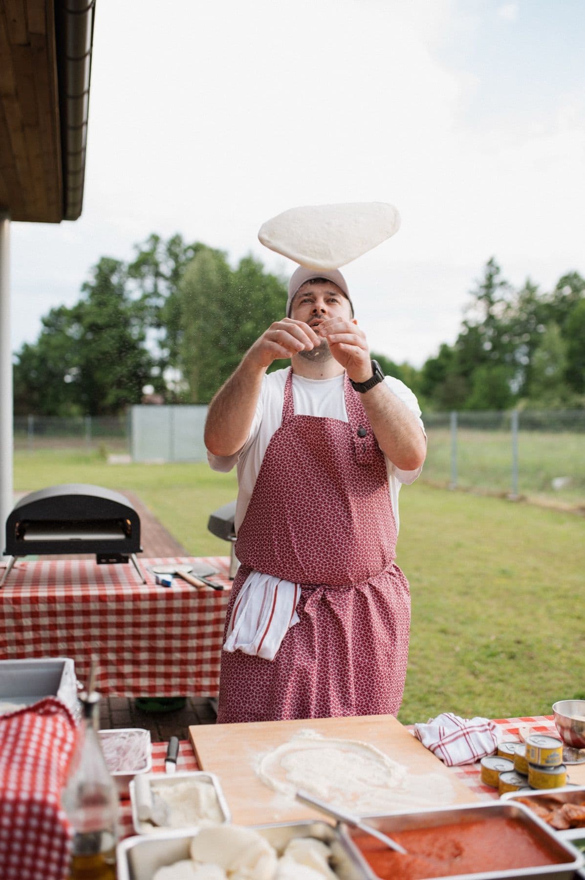 Pizzaiolo Barry Pizza wyrzuca ciasto w powietrze przy mobilnym piecu, obok stanowisko ze składnikami